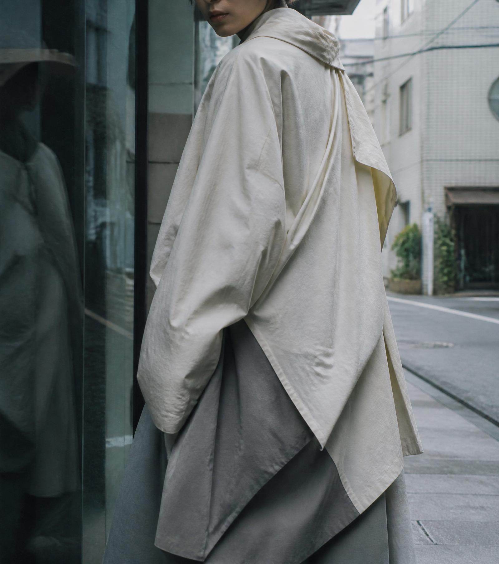A figure turning at a threshold, garment silhouette unresolved.